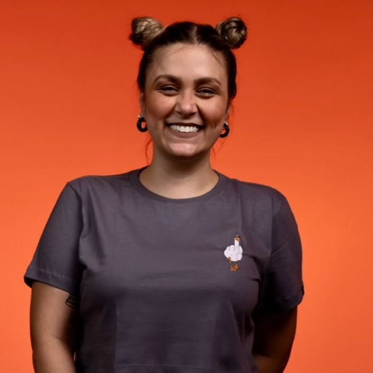 Júlia Calais sorrindo, sobre um fundo laranja